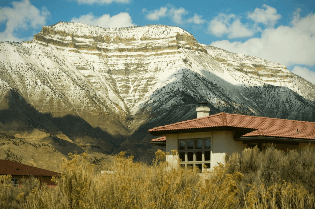 The image shows a house in front of a snowy mountain.