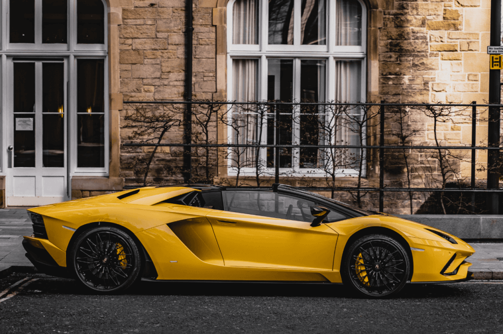 The image shows a yellow luxury car parked in front of a building.