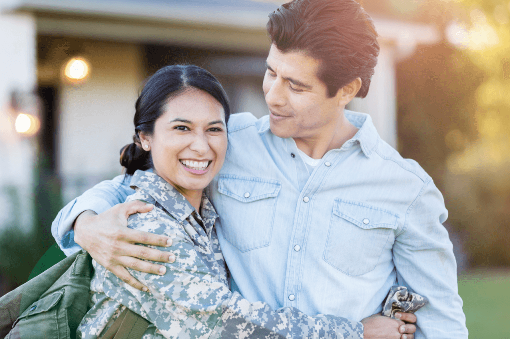 A picture of a daughter in uniform hugging her dad in front of her home.